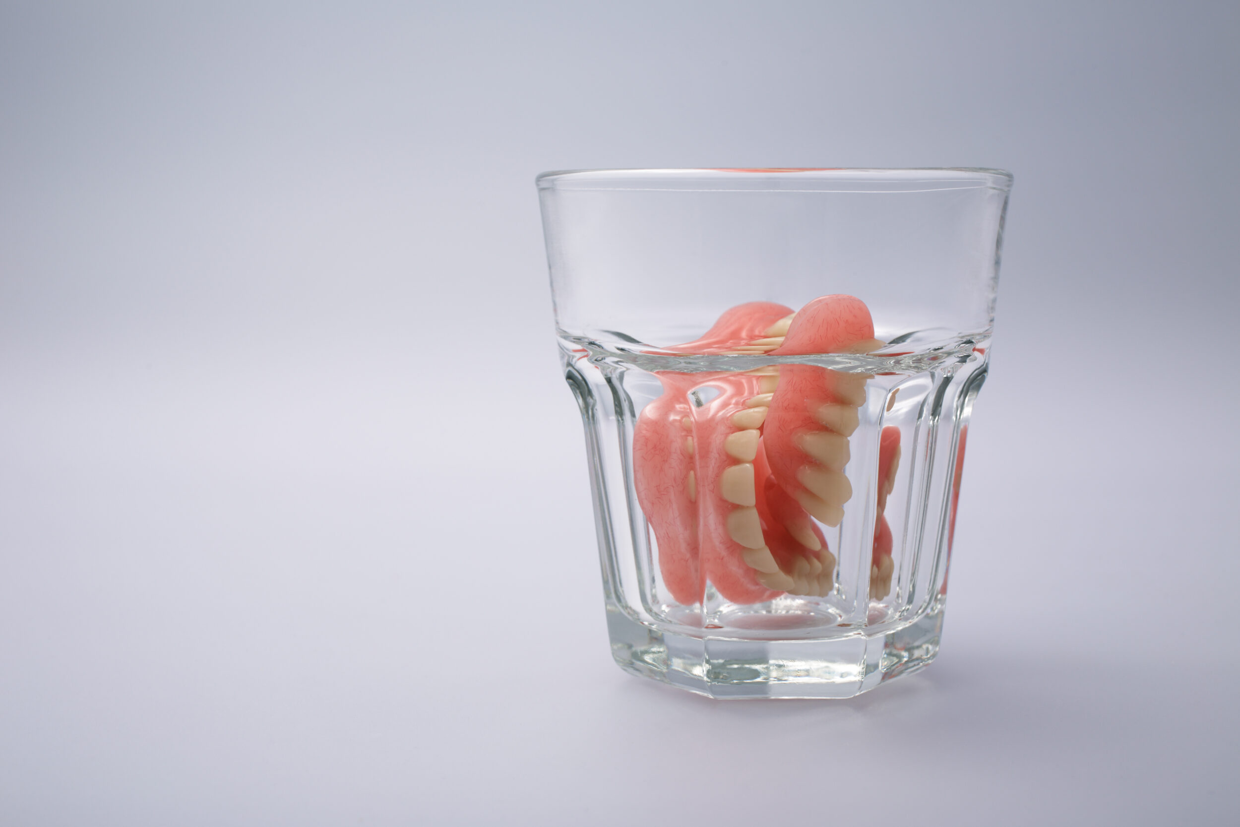 Dentures Sitting In Water Glass